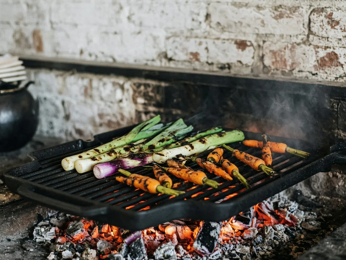 Leeks and carrots charring on a cast iron grill over glowing embers